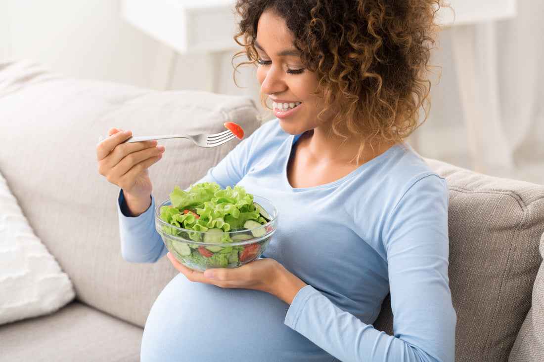 Pregnant woman preparing a colorful, balanced meal at home