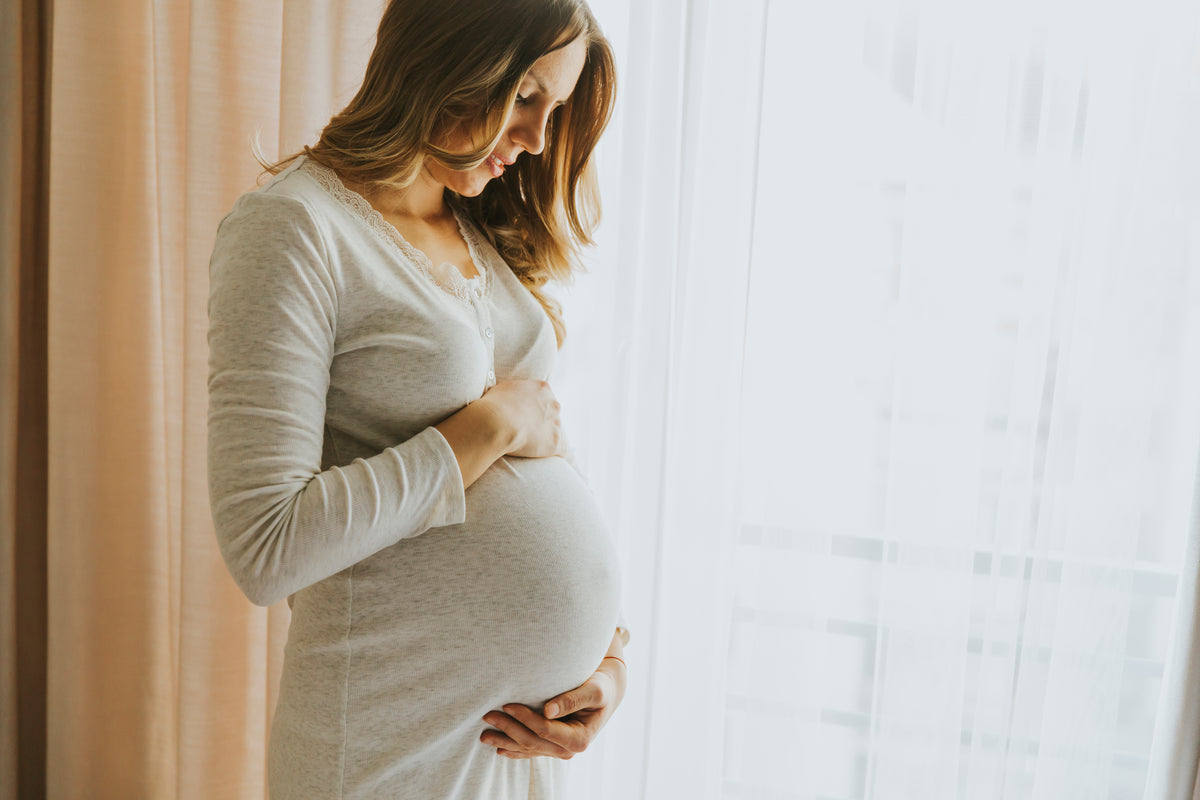 Pregnant woman sitting warmly by a window at home